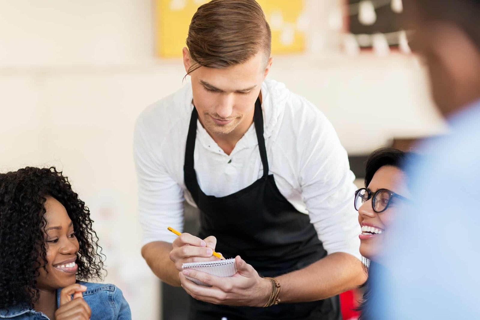 customers and waiter with notepad or restaurant
