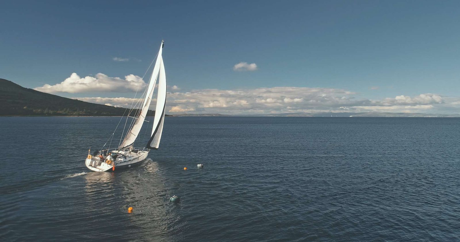 Yacht sail cruise aerial. Sailboat reflect at ocean bay. Mountain coast of Brodick, Arran island